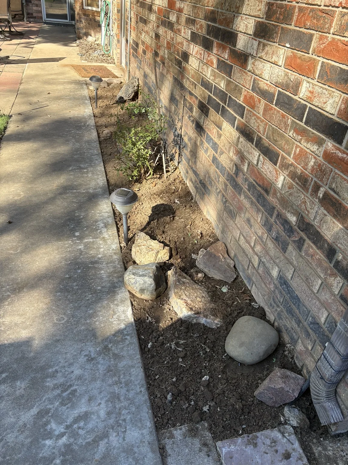 After: weeded garden bed with cleared soil and preserved decorative rocks