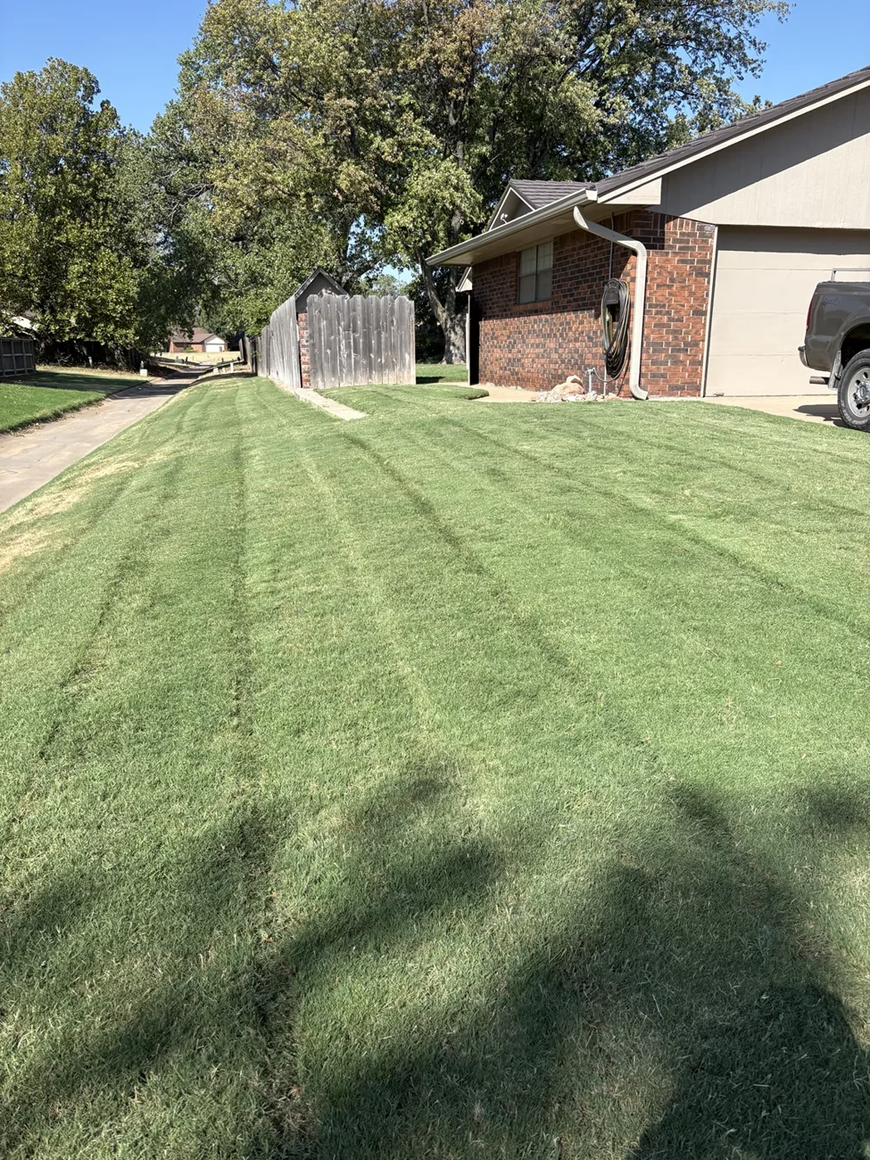 Freshly mowed side lawn beside a brick home